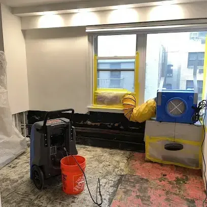 Dehumidifier and air mover drying a room with the flooring pulled up