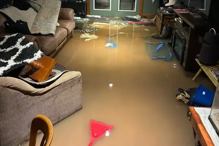 Floodwater standing across a living room floor after a heavy storm