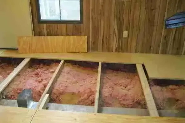 Manufactured home floor opened to show wet insulation between the joists